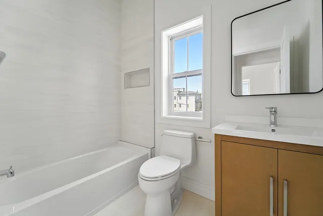 a bathroom with a toilet sink vanity tub and mirror