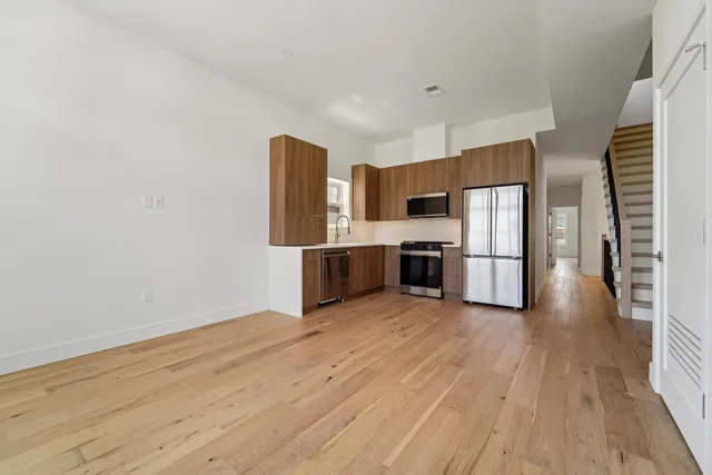 a view of kitchen with wooden floor electronic appliances and cabinets