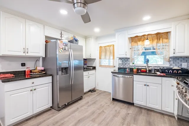 a kitchen with stainless steel appliances a refrigerator a sink cabinets and wooden floor