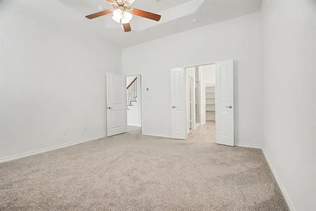 an empty room with chandelier fan and windows