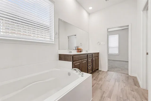 a bathroom with a tub sink and mirror