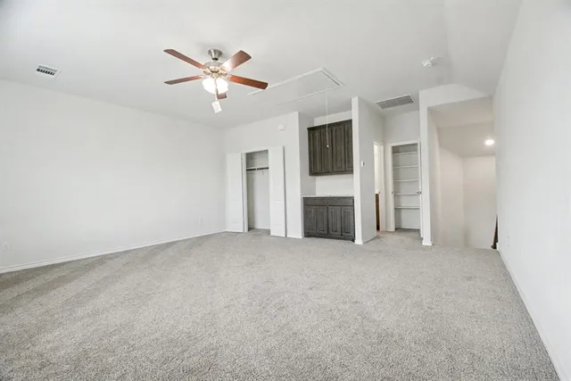 an empty room with closet and a ceiling fan