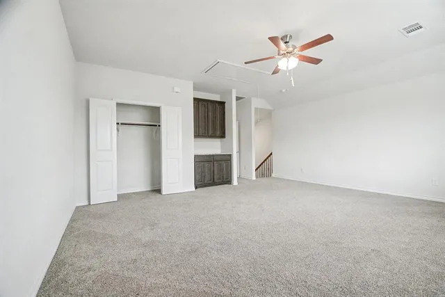 an empty room with closet and a ceiling fan