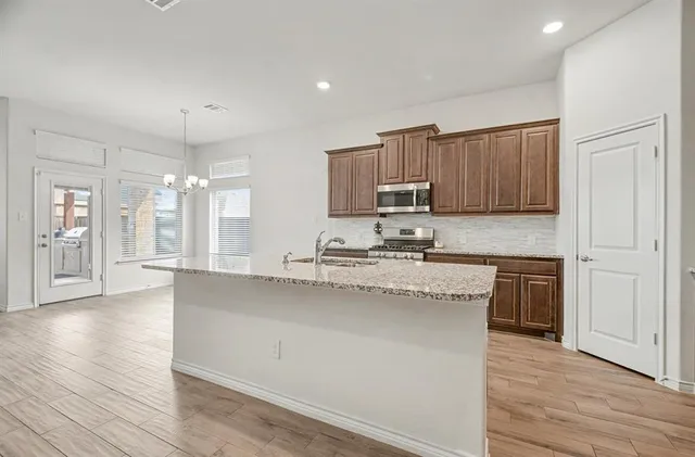 a kitchen with kitchen island granite countertop wooden floors white cabinets and stainless steel appliances