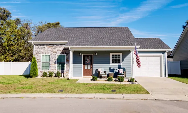a view of a house with a yard potted plants and a table