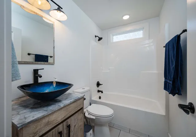 a bathroom with a granite countertop sink a toilet a mirror and bathtub