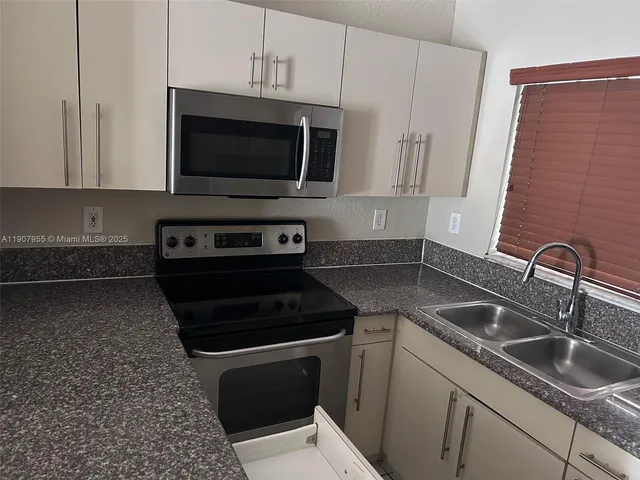 a kitchen with granite countertop a sink and a stove top oven