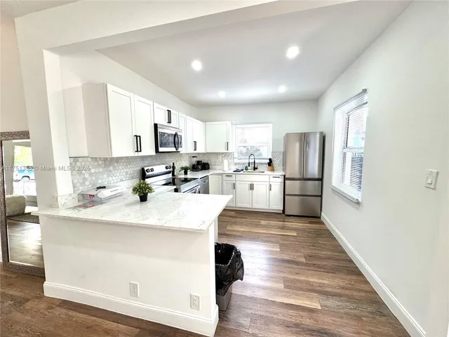 a kitchen with stainless steel appliances granite countertop a refrigerator stove microwave and cabinets