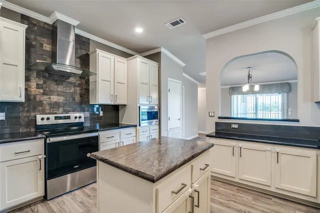 a kitchen with granite countertop stainless steel appliances a sink stove and cabinets