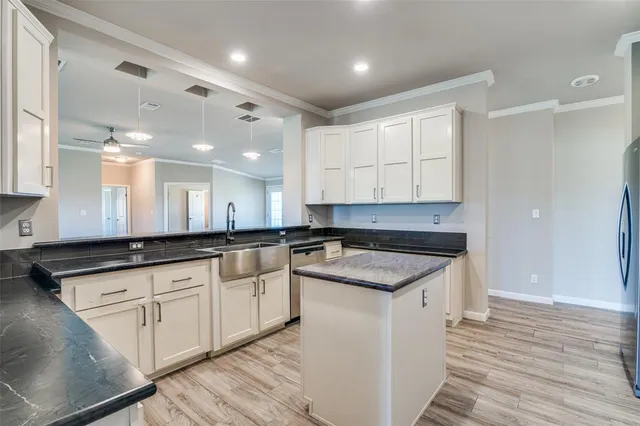 a kitchen with granite countertop a sink and cabinets with wooden floor