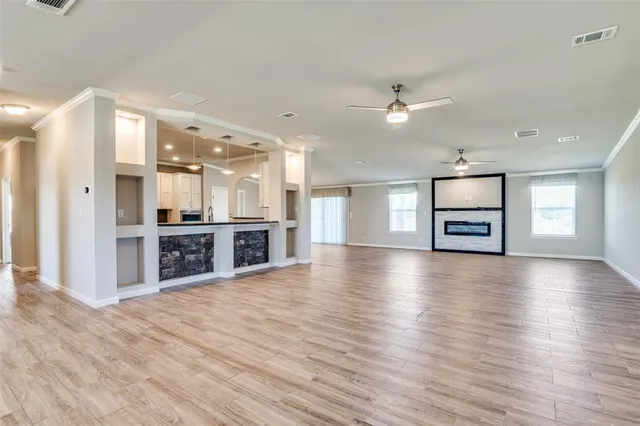 an empty room with wooden floor windows and kitchen view