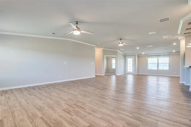 an empty room with wooden floor ceiling fan and window