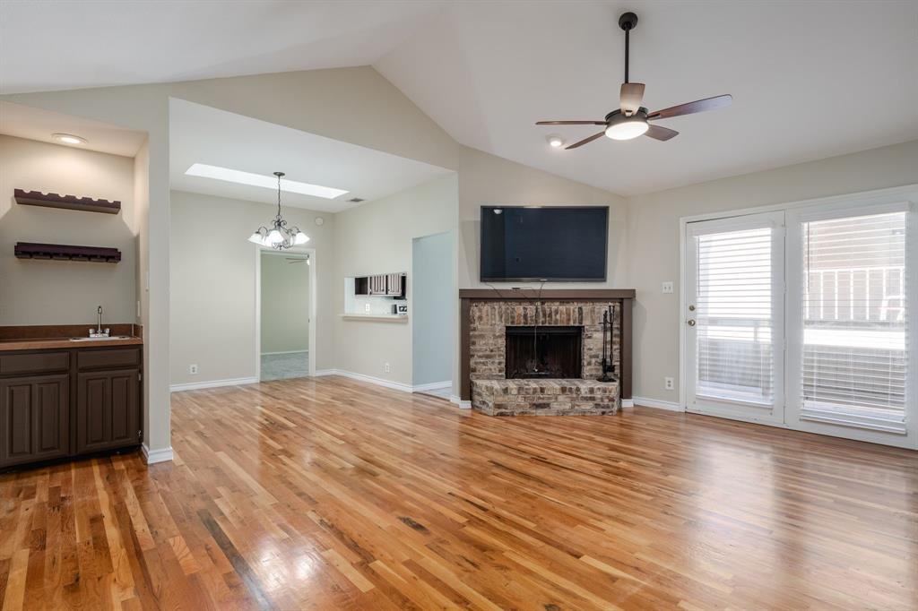 a view of an empty room with wooden floor fireplace and a window