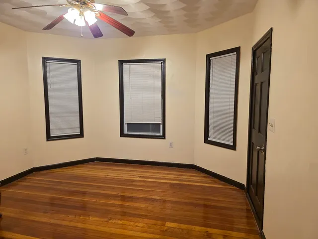 a view of an empty room with window and wooden floor