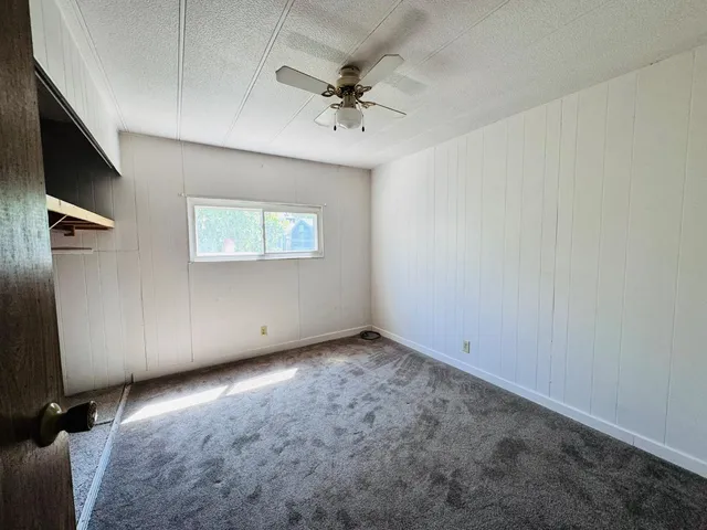 an empty room with a ceiling fan and windows