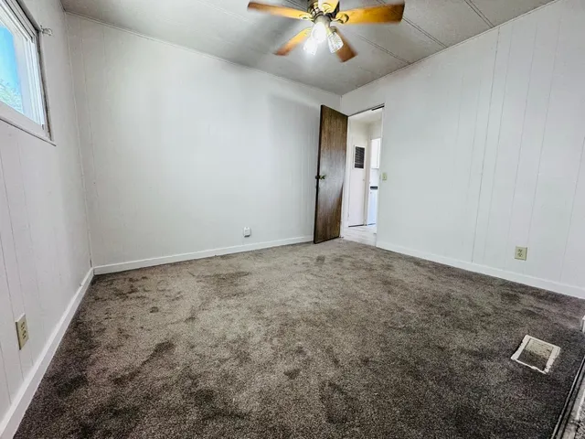 an empty room with a ceiling fan and a window