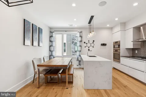 a kitchen with kitchen island a stove a sink a refrigerator and white cabinets with wooden floor