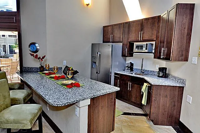 a kitchen with granite countertop kitchen island stainless steel appliances cabinets a sink and a refrigerator
