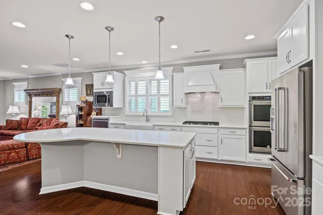 a kitchen with kitchen island white cabinets and stainless steel appliances