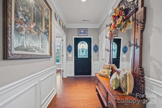 a hallway with painting and a large mirror on a dresser