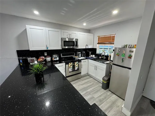 a kitchen with stainless steel appliances a sink a counter top space cabinets and a potted plant