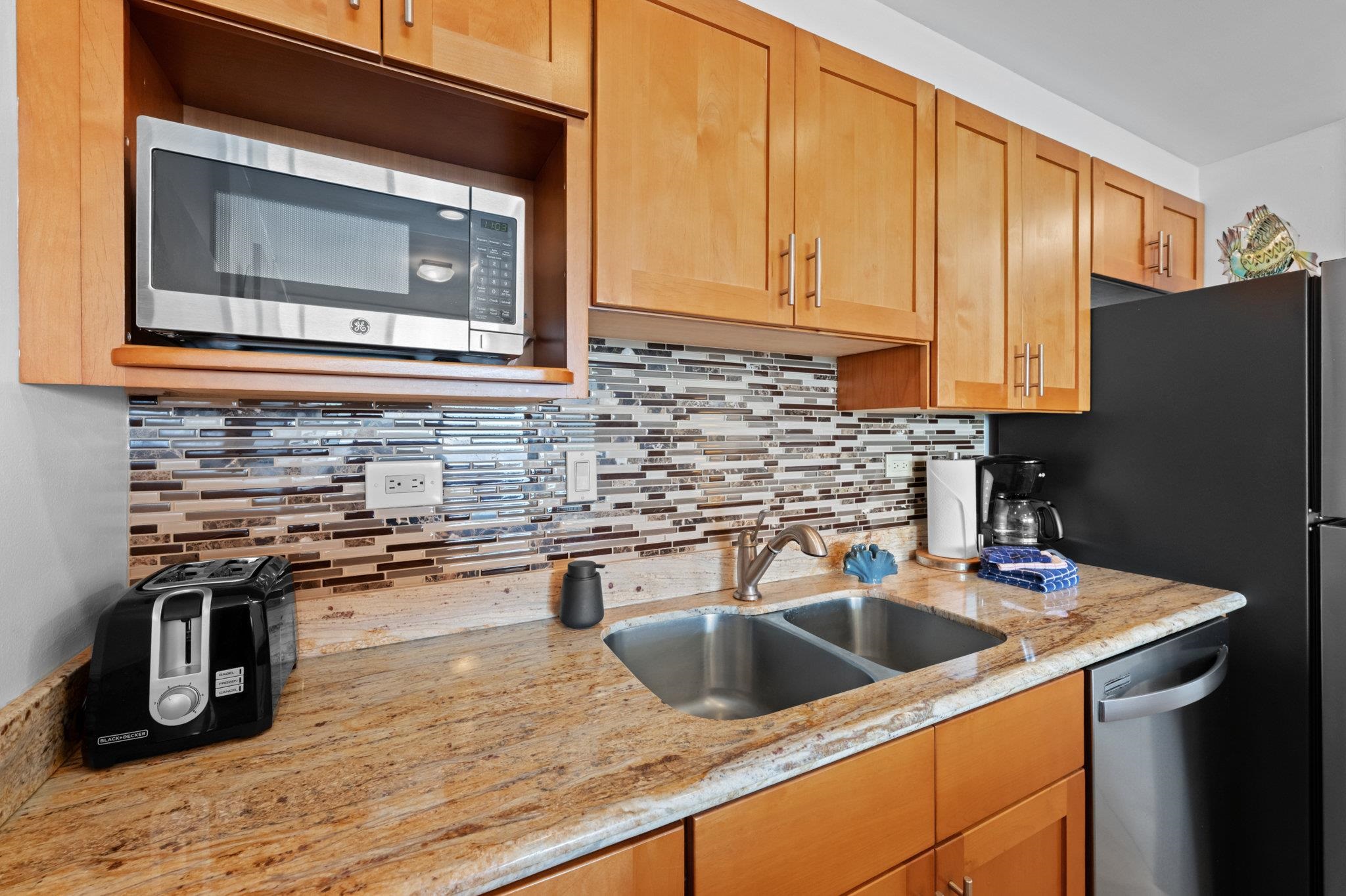 4471 Lower Honoapiilani Road, Unit 415 Lahaina, HI 96761 - Photo 17 of 44 a kitchen with stainless steel appliances granite countertop a sink a stove and a microwave oven with wooden floor