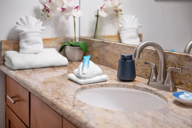 a bathroom with a granite countertop shower sink vanity and toilet