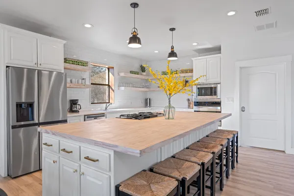 a kitchen with stainless steel appliances a dining table chairs refrigerator and microwave