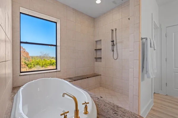 a bathroom with a tub shower and window