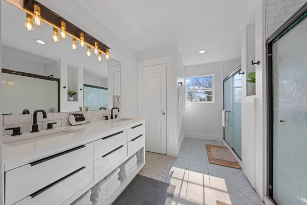 a bathroom with a double vanity sink mirror and shower
