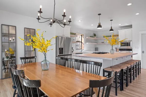 a kitchen with stainless steel appliances kitchen island granite countertop a table chairs and a refrigerator