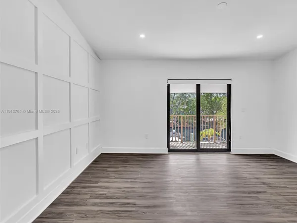 a view of an empty room with wooden floor and painting on the wall