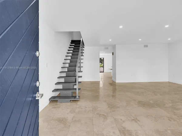 a view of an empty room with wooden floor and stairs