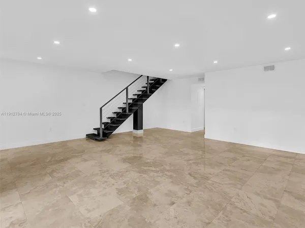 a view of an empty room with wooden floor and windows