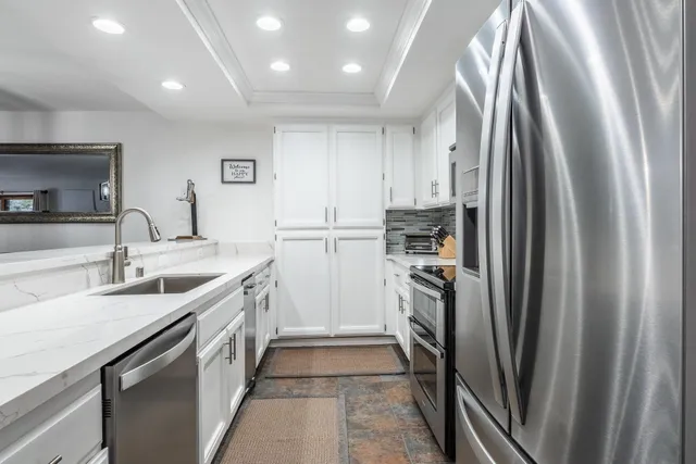 a kitchen with stainless steel appliances granite countertop a refrigerator and a sink