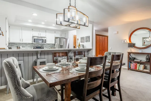 a view of a dining room with furniture a kitchen and chandelier