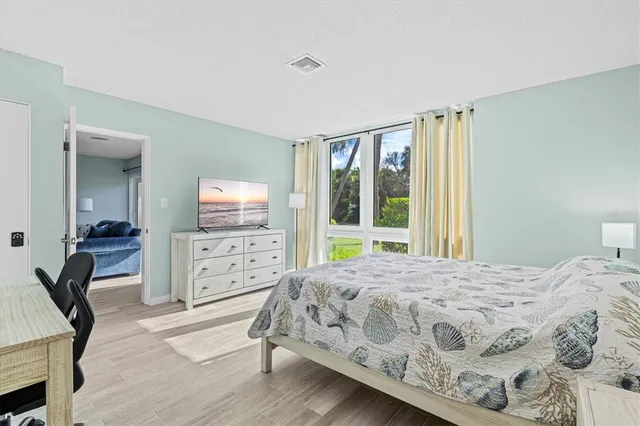 a bedroom with a bed a large window and furniture