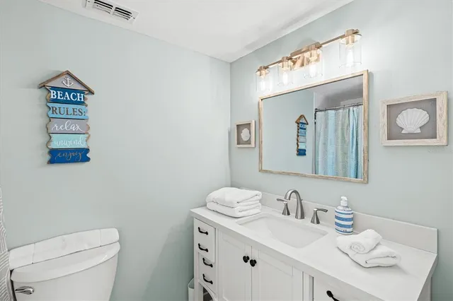 a bathroom with a toilet sink vanity granite and mirror
