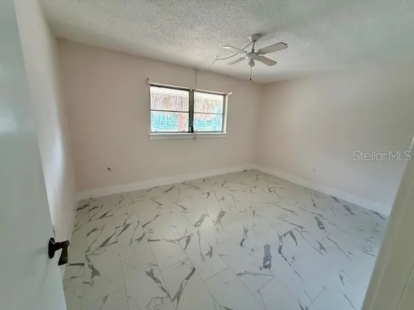 an empty room with a ceiling fan and window