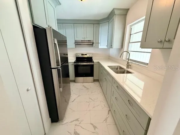 a large kitchen with a refrigerator a sink a stove a microwave and cabinets