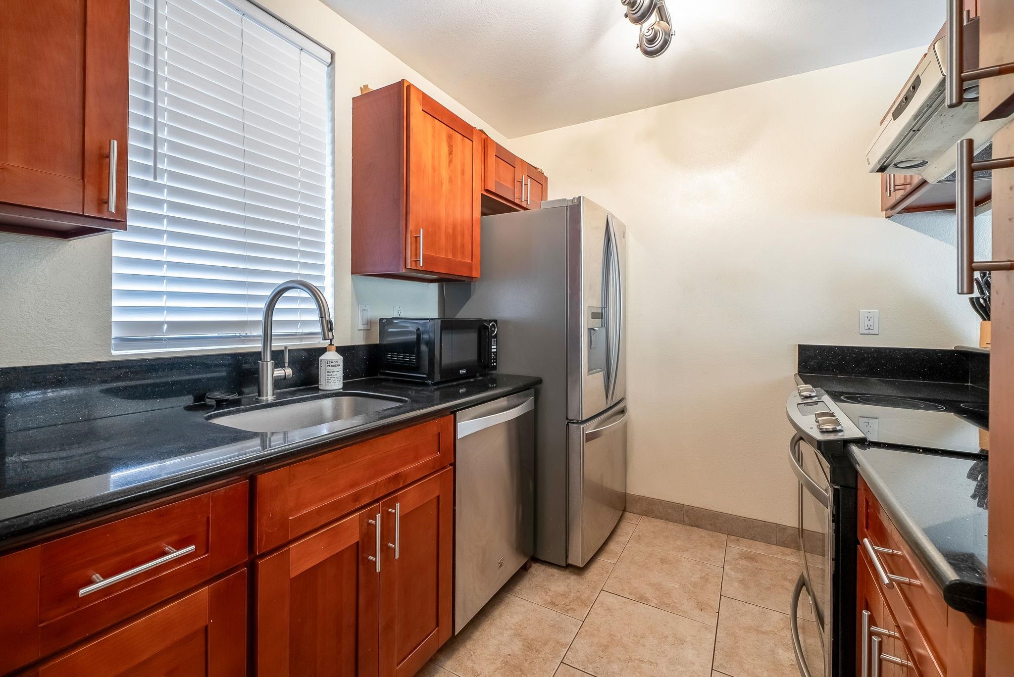 480 Kenolio Road, Unit 6204 Kihei, HI 96753 - Photo 20 of 44 a kitchen with stainless steel appliances granite countertop a refrigerator and a sink