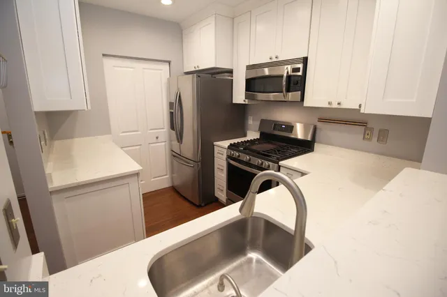 a kitchen with stainless steel appliances a refrigerator a sink a stove a microwave a counter top space and cabinets
