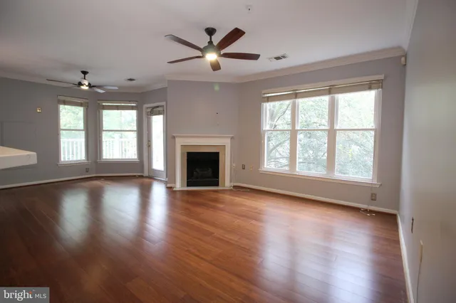 an empty room with wooden floor fireplace and windows