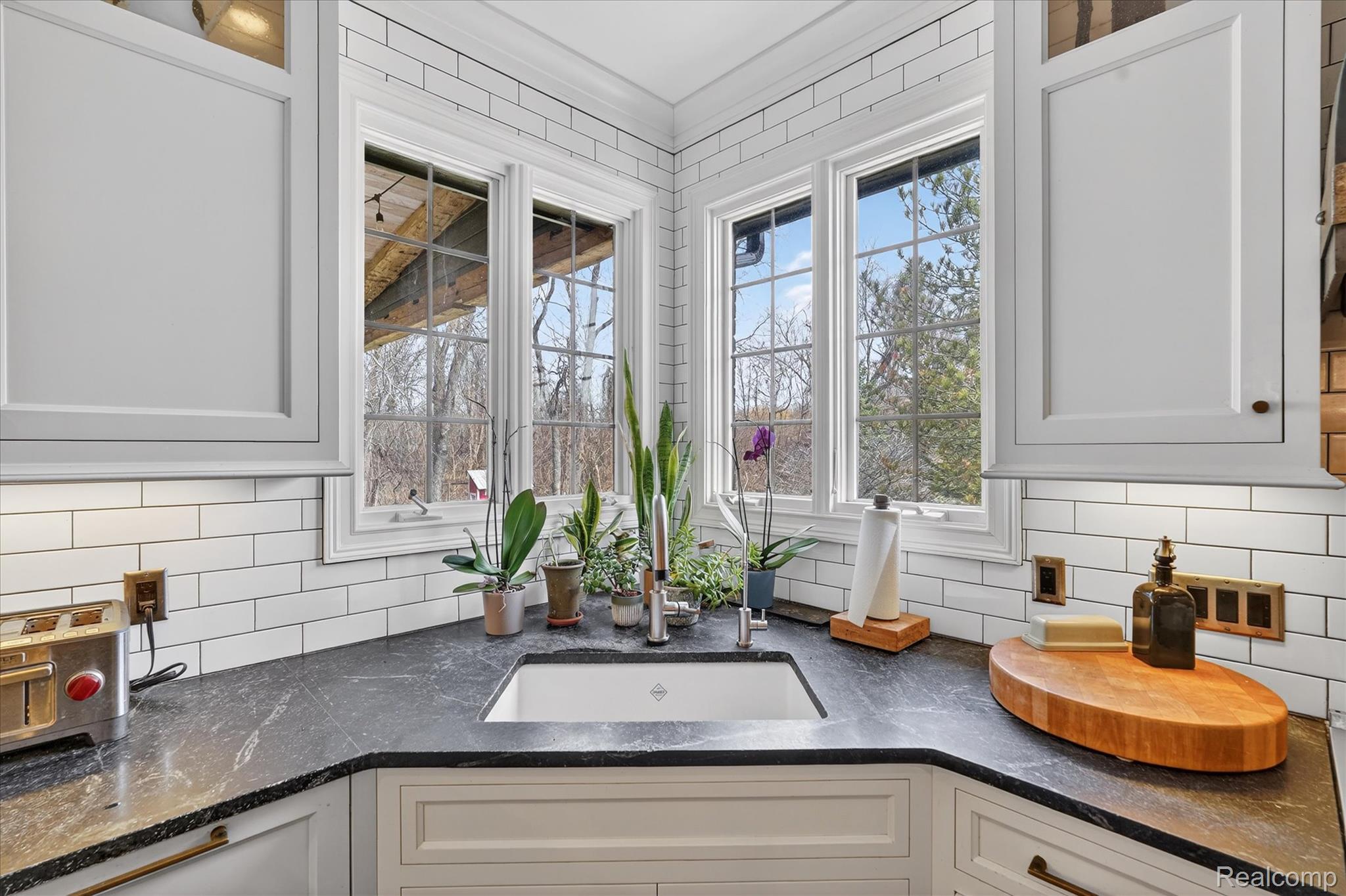6932 Oakhurst Ridge Road Clarkston, MI 48348 - Photo 17 of 78 Kitchen with dark stone counters, white cabinets, ornamental molding, and tasteful backsplash