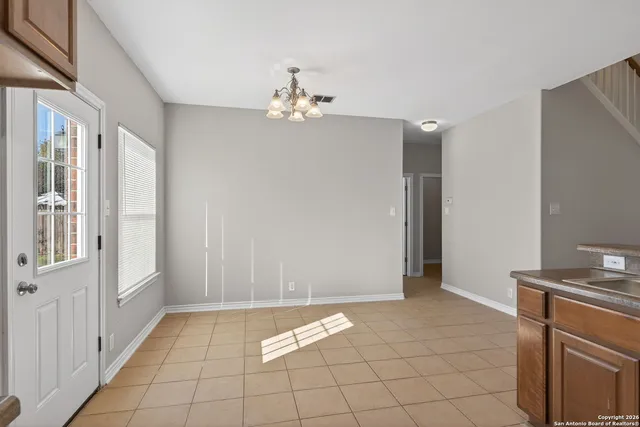 a kitchen with stainless steel appliances granite countertop white cabinets a refrigerator a sink a stove a dining table and chairs