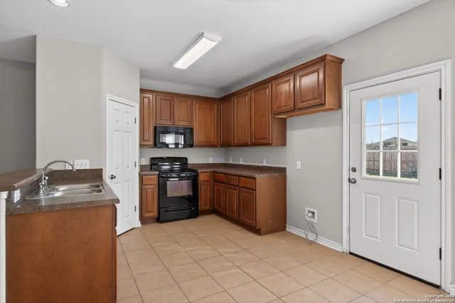 a kitchen with granite countertop a stove top oven sink and cabinets