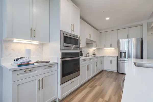 a kitchen with stainless steel appliances kitchen island granite countertop a table chairs and a refrigerator
