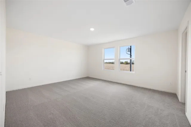 an empty room with windows and refrigerator
