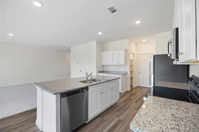 a large kitchen with stainless steel appliances granite countertop a white stove top oven and white cabinets