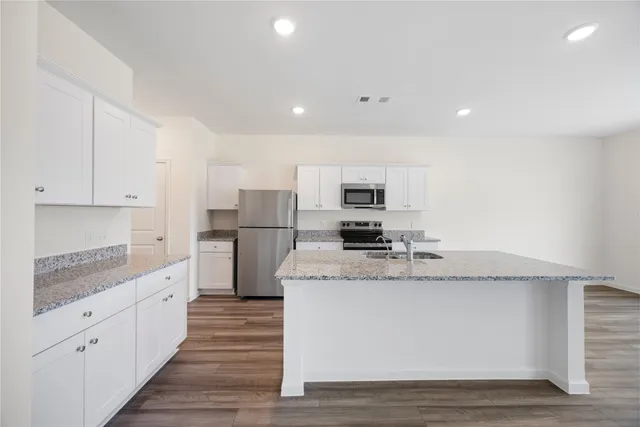 a kitchen with granite countertop a sink stove and refrigerator